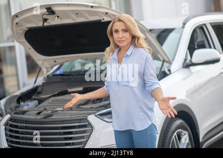 Verzweifelte Frau, die in der Nähe des Autos auf die Kamera schaute Stockfoto