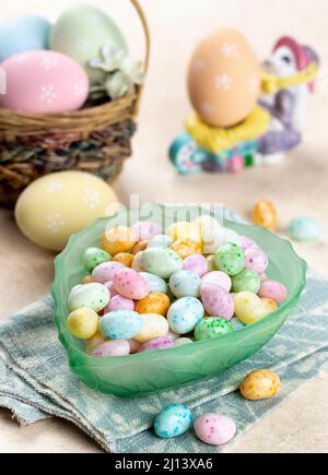 Schüssel mit osterbonbons und pastellfarbenen Eiern auf einem Tisch Stockfoto