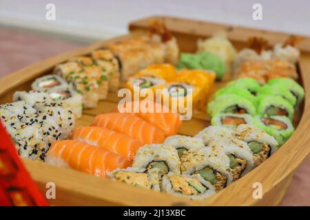 Sushi-Brötchen im Set. Traditionelles japanisches Sushi und Brötchen mit frischem Lachs, Thunfisch, Aal und Garnelen auf Reis. Auf Holzplatte servieren Stockfoto