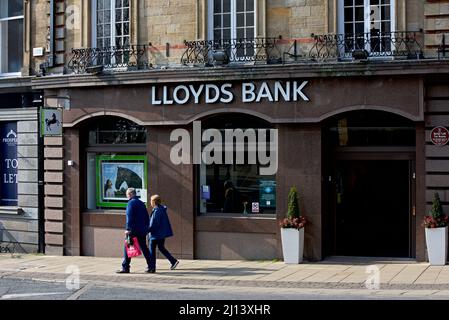 Mann und Frau, die an der Zweigstelle der NatWest Bank am Cambridge Crescent, Harrogate, North Yorkshire, England, vorbeigehen Stockfoto