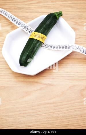 Biodynamische ökologische Landwirtschaft und Ernährung Konzept - frische gesunde Zucchini in einer weißen Keramikplatte auf Holztisch mit Platz für Text Stockfoto