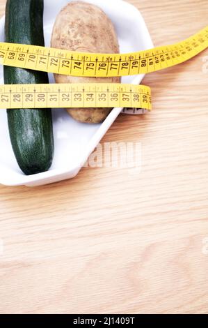 Biodynamische ökologische Landwirtschaft und Ernährung Konzept - frische gesunde Zucchini und Kartoffeln in einer weißen Keramikplatte auf Holztisch mit Platz für Text Stockfoto