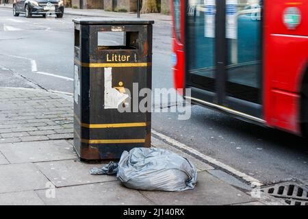 Eine Mülltüte neben einem Abfalleimer, London, Großbritannien Stockfoto