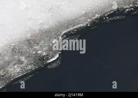 Schmelzendes Eis auf dem See. Eiskante an der gefrorenen Küste, frühe Frühjahrssaison Stockfoto