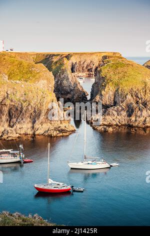 Die ruhigen Buchten an der felsigen Küste der Insel Belle Ile en Mer bieten einen geschützten Ankerplatz für viele Segelboote im ruhigen Sonnenuntergang. Stockfoto