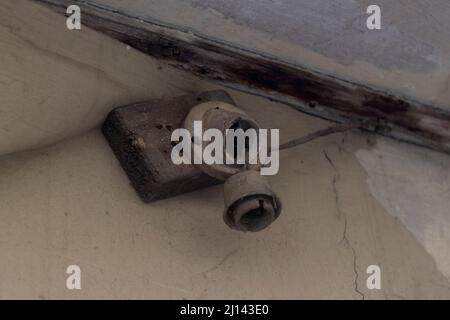 Alte, beschädigte Lampenfassung ohne Glühlampe an einer gerissenen Wand Stockfoto