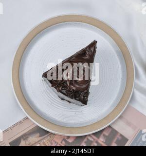 Ein Stück hausgemachter Schokoladenkuchen auf einem weißen Gericht auf dem Tisch Stockfoto