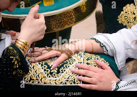 Künstlerin, die Henna-Tätowierung auf Frauenhänden anwendet. Mehndi ist traditionelle marokkanische Dekorationskunst. Nahaufnahme, Draufsicht Stockfoto