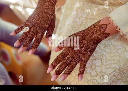 Künstlerin, die Henna-Tätowierung auf Frauenhänden anwendet. Mehndi ist traditionelle marokkanische Dekorationskunst. Nahaufnahme, Draufsicht Stockfoto