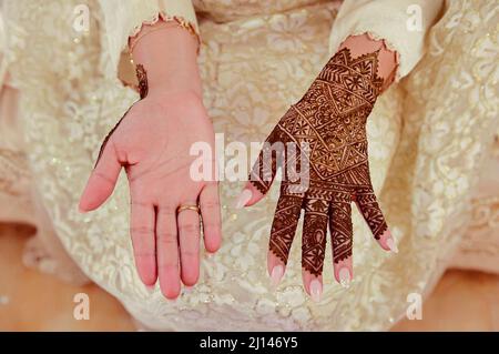 Künstlerin, die Henna-Tätowierung auf Frauenhänden anwendet. Mehndi ist traditionelle marokkanische Dekorationskunst. Nahaufnahme, Draufsicht Stockfoto