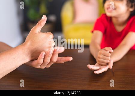 Hispanischer Vater und Sohn sprechen durch die Gebärdensprache, während sie am Esstisch sitzen Stockfoto