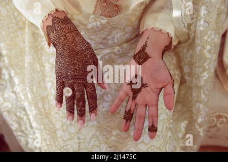 Künstlerin, die Henna-Tätowierung auf Frauenhänden anwendet. Mehndi ist traditionelle marokkanische Dekorationskunst. Nahaufnahme, Draufsicht Stockfoto