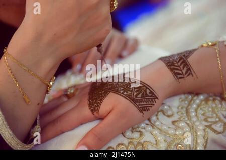 Künstlerin, die Henna-Tätowierung auf Frauenhänden anwendet. Mehndi ist traditionelle marokkanische Dekorationskunst. Nahaufnahme, Draufsicht Stockfoto