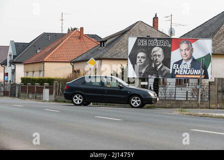 Autopass durch Wahlplakat für Fidesz Partei auf der Straße von Mosonmagyarovar platziert. Auf der Plakatwand (von links nach rechts) der Oppositionsführer Peter Marki-Zay, der ehemalige Premierminister Ferenc Gyurcsany und der ungarische Premierminister und Führer von Fidesz Viktor Orban. Mosonmagyarovar ist die Stadt im Nordwesten Ungarns, etwa 160 Kilometer von der ungarischen Hauptstadt Budapest entfernt. Peter Marki-Zay wird Premierminister Viktor Orban bei den bevorstehenden Parlamentswahlen, die am 3.. April 2022 stattfinden werden, herausfordern. Stockfoto