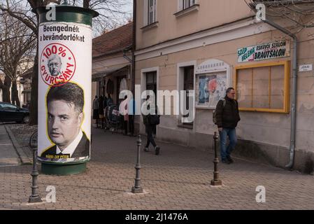 Fußgänger kommen auf der Straße an einem Wahlplakat von Peter Marki-Zay, dem Führer der für Ungarn Vereinigten ungarischen Oppositionskoalition, vorbei. Mosonmagyarovar ist die Stadt im Nordwesten Ungarns, etwa 160 Kilometer von der ungarischen Hauptstadt Budapest entfernt. Peter Marki-Zay wird Premierminister Viktor Orban bei den bevorstehenden Parlamentswahlen, die am 3.. April 2022 stattfinden werden, herausfordern. Stockfoto