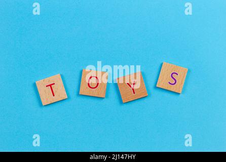 Das Wort Spielzeug, Dinkel mit hölzernen Buchstabensteine über blauen Hintergrund. Ansicht von oben Stockfoto