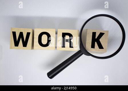 Lupe über dem Wort Job Holzbuchstaben auf gelbem Hintergrund. Draufsicht, flach liegend. Stockfoto