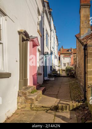 Traditionelle, weiß gerenderte Küstenhütten an einer schmalen Gasse in Robin Hood's Bay, North Yorkshire. VEREINIGTES KÖNIGREICH Stockfoto