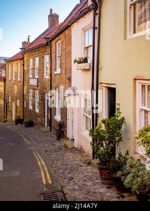 Eine Reihe traditioneller Terrassenhäuser an einer steilen Straße Robin Hoods Bay, North Yorkshire. Stockfoto