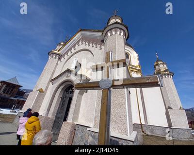 Slawske, Ukraine. 20. März 2022. Ein Kreuz vor der Mariä-Himmelfahrtskirche der griechisch-katholischen Kirche im karpatischen Dorf in der Westukraine erinnert an den 1000.. Jahrestag der Taufe der Rus im Jahr 1988. (To dpa 'das friedliche Leben im angegriffenen Land') Quelle: Andreas Stein/dpa/Alamy Live News Stockfoto