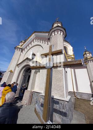 Slawske, Ukraine. 20. März 2022. Ein Kreuz vor der Mariä-Himmelfahrtskirche der griechisch-katholischen Kirche im karpatischen Dorf in der Westukraine erinnert an den 1000.. Jahrestag der Taufe der Rus im Jahr 1988. (To dpa 'das friedliche Leben im angegriffenen Land') Quelle: Andreas Stein/dpa/Alamy Live News Stockfoto