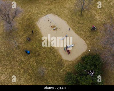 Drohnenaufnahme eines Spielplatzes auf dem Feld, umgeben von ein paar blattlosen Bäumen. Stockfoto