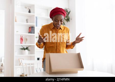 Aufgeregt schwarze Dame öffnen Lieferbox zu Hause Stockfoto