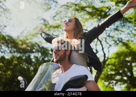 Born to Wander, Born to Wandern. Kurzer Screenshot eines jungen attraktiven Paares, das mit einem Roller durch die Stadt fährt. Stockfoto