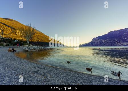 Nago–Torbole, Italien - 26. Februar 2022: Blick auf das Nordufer des Gardasees, mit Einheimischen und Besuchern, an einem klaren Wintertag, in Nago–Torbole, Tren Stockfoto