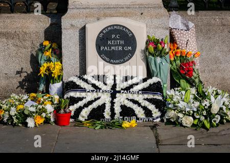 London, Großbritannien. 22. März 2022. Weitere Ehrungen und Blumen sind auf dem Gedenkstein für PC Keith Palmer vor dem Parlament erschienen. An der Westminster Bridge wird mit einer Schweigeminute, einem kurzen Gottesdienst und Reden eine Gedenktafel an diejenigen enthüllt, die am 22.. März 2017 bei den Terroranschlägen auf der Westminster Bridge und dem New Palace Yard ihr Leben verloren haben. An der Veranstaltung nehmen Familien und Freunde der Opfer sowie Priti Patel, Sadiq Khan, Polizei- und Rettungsdienste sowie Parlamentsabgeordnete Teil. Kredit: Imageplotter/Alamy Live Nachrichten Stockfoto