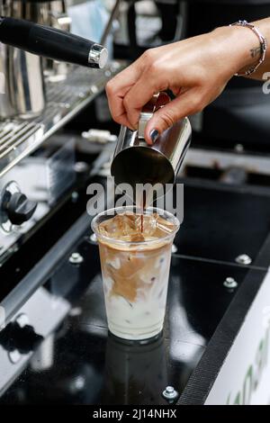 Eiskaffee wird zubereitet. Kaffee mit Milch und Eis in das Glas gießen. Stockfoto
