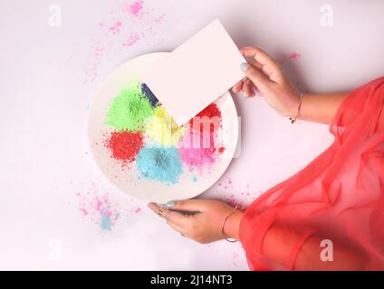 Draufsicht auf eine Erwachsene weibliche Hand, die mit einem weißen Papier farbigen Zucker auf einem weißen Teller trennt Stockfoto