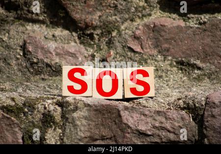 Hölzerne Blöcke bilden die Buchstaben SOS isoliert auf weißem Hintergrund Stockfoto