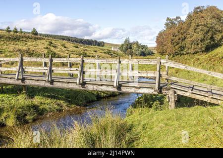 Eine hölzerne Fußgängerbrücke über Conglass Water bei Blairnamarrow in der Nähe von Tomintoul, Moray, Schottland, Großbritannien. Stockfoto