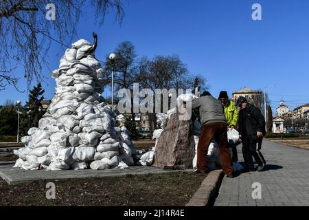 ZAPORIZHZHIA, UKRAINE - 22. MÄRZ 2022 - örtliche Freiwillige, Historiker und Museumsmitarbeiter legen Sandsäcke um das Denkmal des ukrainischen Gewichtheber, Stockfoto