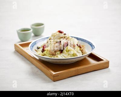 Handgeschredderter Kohl mit Schweineschnitzel in einer Schale isoliert auf Holzbrett Seitenansicht auf grauem Hintergrund Stockfoto