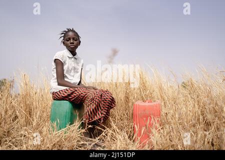 Black African Girl traurig, weil sie hart auf den Feldern arbeiten muss, anstatt zur Schule zu gehen.Kinderarbeit Konzept. Stockfoto