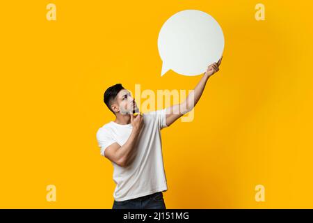 Nachdenklicher Mann aus dem Nahen Osten mit leerer Sprechblase auf Gelb Stockfoto