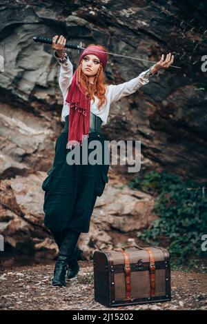 Outdoor-Porträt einer jungen Frau im Piratenkostüm mit einem Schwert. Stockfoto