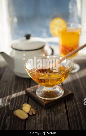 Glas mit Honig und heißem Getränk mit Sanddornbeere, Ingwer, Zitrone vor dem Hintergrund des Fensters Stockfoto