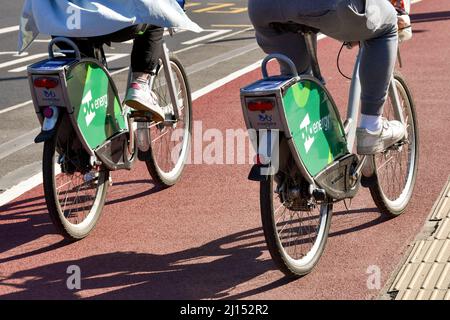 Cardiff, Wales - März 2022: Rückansicht von zwei Personen, die Fahrräder fahren, die von einem Fahrradverleihsystem im Stadtzentrum gemietet wurden Stockfoto