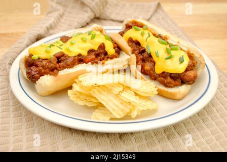 Beladen Chilli Dog mit Cheddar-Käse und Scallion serviert mit gewellten Kartoffelchips Stockfoto