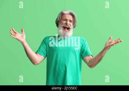 Wütender älterer Mann im T-Shirt auf grünem Hintergrund Stockfoto
