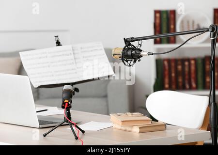 Moderner Arbeitsplatz mit Laptop, Büchern und Mikrofonen im Zimmer Stockfoto