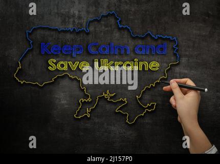 Girl zeichnet eine Landkarte der Ukraine mit dem Text Keep calm and rette die Ukraine auf der Tafel Stockfoto