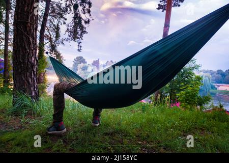 Mann, der im Freien in einer Hängematte liegt. Stockfoto