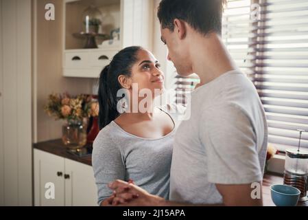 Er weiß nur, wie ich mein Herz einen Schlag überspringen kann. Eine kurze Aufnahme eines glücklichen jungen Paares, das langsam in der Küche tanzt. Stockfoto