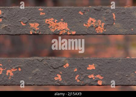 Nahaufnahme, Makroaufnahme von abblätternder orangefarbener und brauner Farbe auf Eisenmetallstäben machen eine düstere, urbane Textur mit Bokeh-Effekt Hintergrund Stockfoto