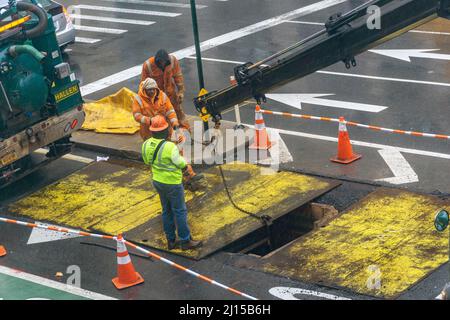 Arbeiter ersetzen eine Stahlplatte über der Fahrbahn, nachdem sie am Mittwoch, dem 9. März 2022, in der Ninth Avenue in Chelsea in New York unterirdisch gearbeitet haben. (© Richard B. Levine) Stockfoto