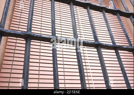Detail eines alten geschmiedeten Zauns auf einem antiken Fenster mit einem Fensterladen Stockfoto